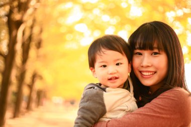 Genç Asyalı anne oğluyla parkta eğleniyor.  