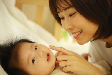 Genç Asyalı anne içeride küçük kızı oynuyor.