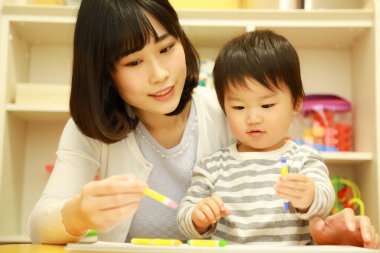 Anne ve oğul beyaz kağıda boya kalemleri çiziyor.