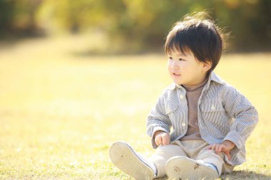 Parkta oturan sevimli Asyalı çocuk. 