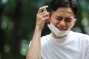 Maske takan ve kulak ağrısı çeken bir adam.