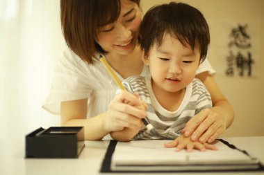 Anne ve oğul fırçayla yazı alıştırması yapıyorlar.