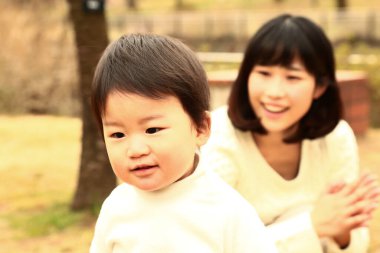 Genç Asyalı anne oğluyla parkta eğleniyor.  