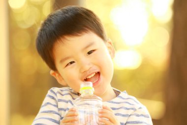 Küçük çocuk şişeden su içiyor.