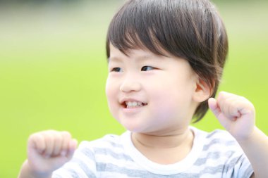  Parktaki sevimli Asyalı çocuk gülümsüyor. 