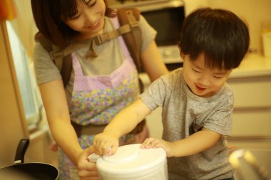 Anne ve oğul mutfakta birlikte yemek pişiriyorlar. 