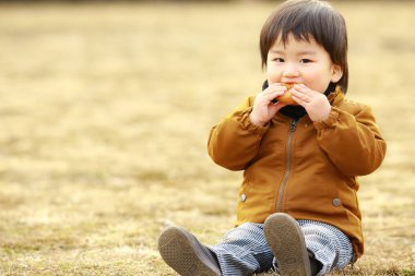 Parkta kurabiyesi olan küçük sevimli bir çocuk.