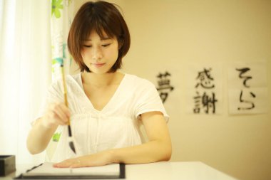 Genç Japon kadın fırçayla yazı pratiği yapıyor.