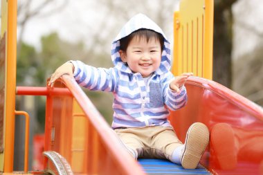 Mutlu küçük çocuk oyun bahçesinde oynuyor