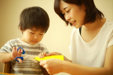 Genç Asyalı anne küçük oğluyla oynuyor.