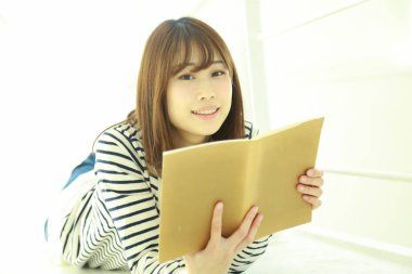 Güzel genç Asyalı kadın kitap okuyor. 