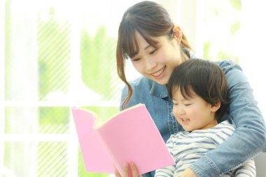 Küçük sevimli oğlu olan genç bir anne evde kitap okuyor.