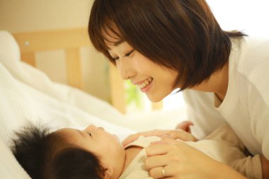 Genç Asyalı anne evde küçük bebekle eğleniyor. 