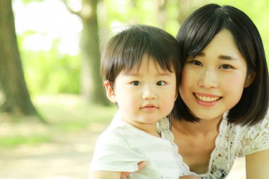 Genç Asyalı anne oğluyla parkta eğleniyor.  