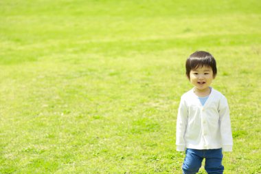 Parktaki çimenlikteki Asyalı küçük çocuk. 