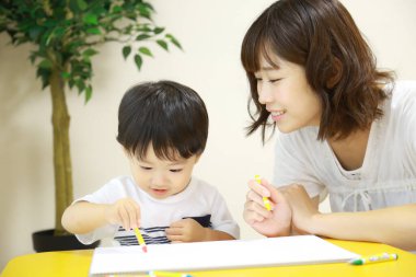 Anne ve oğul beyaz kağıda boya kalemleri çiziyor.