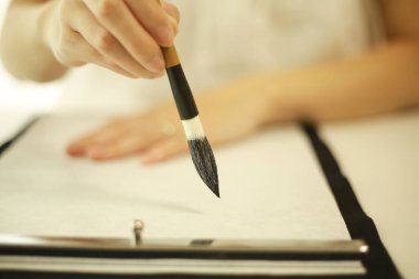 Genç Japon kadın fırçayla yazı pratiği yapıyor.