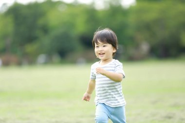 Asyalı küçük çocuk parkta eğleniyor. 