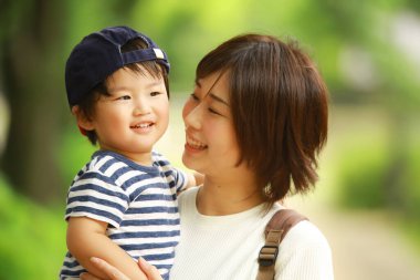 Genç anne ve sevimli küçük oğlu parkta birlikte oynuyorlar.