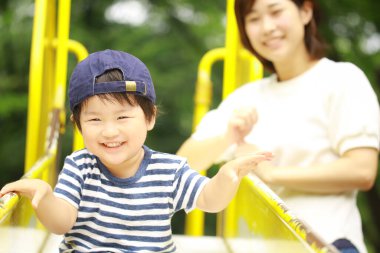 Genç anne ve sevimli mutlu küçük oğul parkta birlikte oynuyorlar.