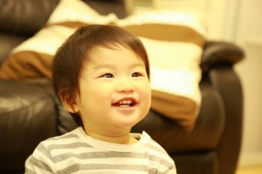 Küçük tatlı Asyalı çocuk evde oturuyor.