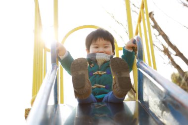 Küçük çocuk oyun bahçesinde oynuyor.