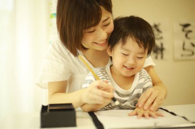 Anne ve oğul fırçayla yazı alıştırması yapıyorlar.