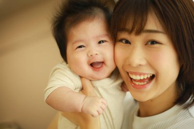 Genç Asyalı anne evde küçük bebekle eğleniyor. 