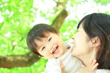 Genç Asyalı anne oğluyla parkta eğleniyor.  