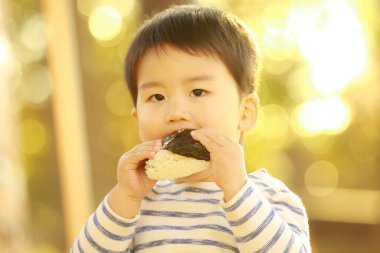 Parkta çörek yiyen küçük çocuk.