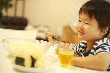 Asyalı şirin çocuk mutfakta yemek yiyor.