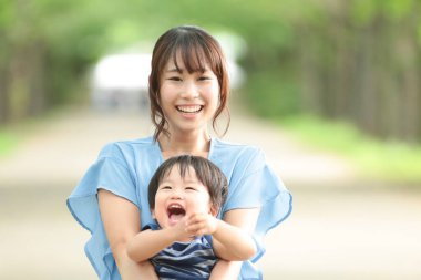 Genç Asyalı anne ve küçük oğlu parkta eğleniyorlar.  