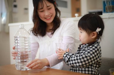 Asyalı bir aile evdeki şişeden su içiyor.