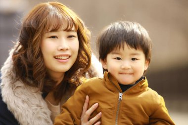 Genç Asyalı anne oğluyla parkta eğleniyor.  