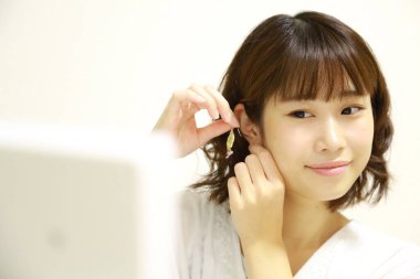 Genç Asyalı kadın aynaya makyaj yapıyor.