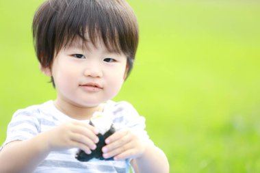 Parkta yiyecekleri olan Asyalı küçük bir çocuk. 