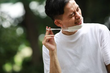 Maske takan ve kulak ağrısı çeken bir adam.