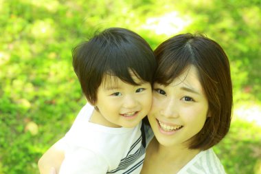 Genç Asyalı anne oğluyla parkta eğleniyor.  