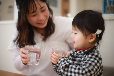 Anne ve kızı musluk suyu içiyor.
