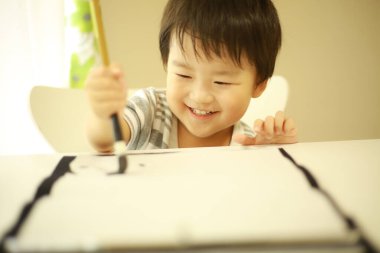 Küçük Japon çocuk fırça kaligrafi ile pratik yapıyor.