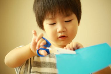 Küçük çocuk kağıt ve makasla oynuyor.