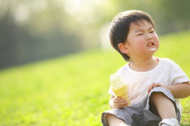 Çimlerin üzerinde dondurması olan küçük tatlı bir çocuk.
