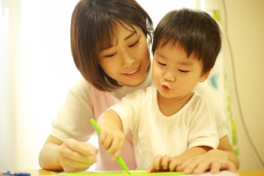 Annesiyle resim yapan küçük sevimli bir çocuk. 