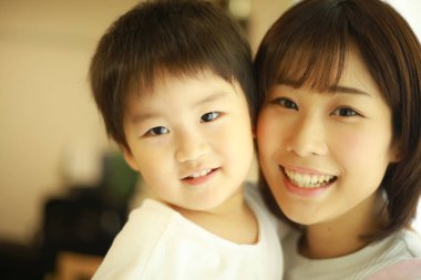 Asyalı genç kadın ve küçük oğlu kucaklaşıyorlar.   