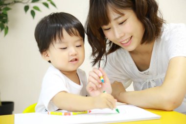 Anne ve oğul beyaz kağıda boya kalemleri çiziyor.