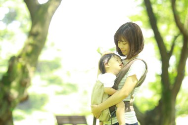 Genç Asyalı anne ve çocuğu parkta uyuyor.  