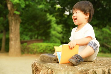 Parkta kitabı olan Asyalı küçük çocuk. 
