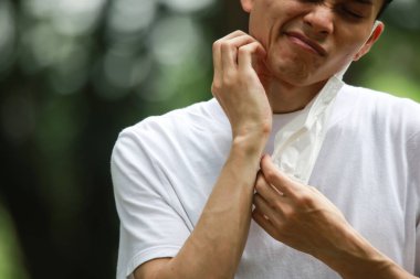 Maske takan ve kulak ağrısı çeken bir adam.