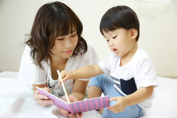 Schöne Asiatin Liest Buch Mit Ihrem Kleinen Sohn — Stockfoto