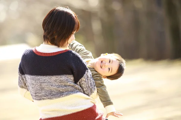 若いお母さんとかわいい小さな息子が公園で遊んでいます — ストック写真